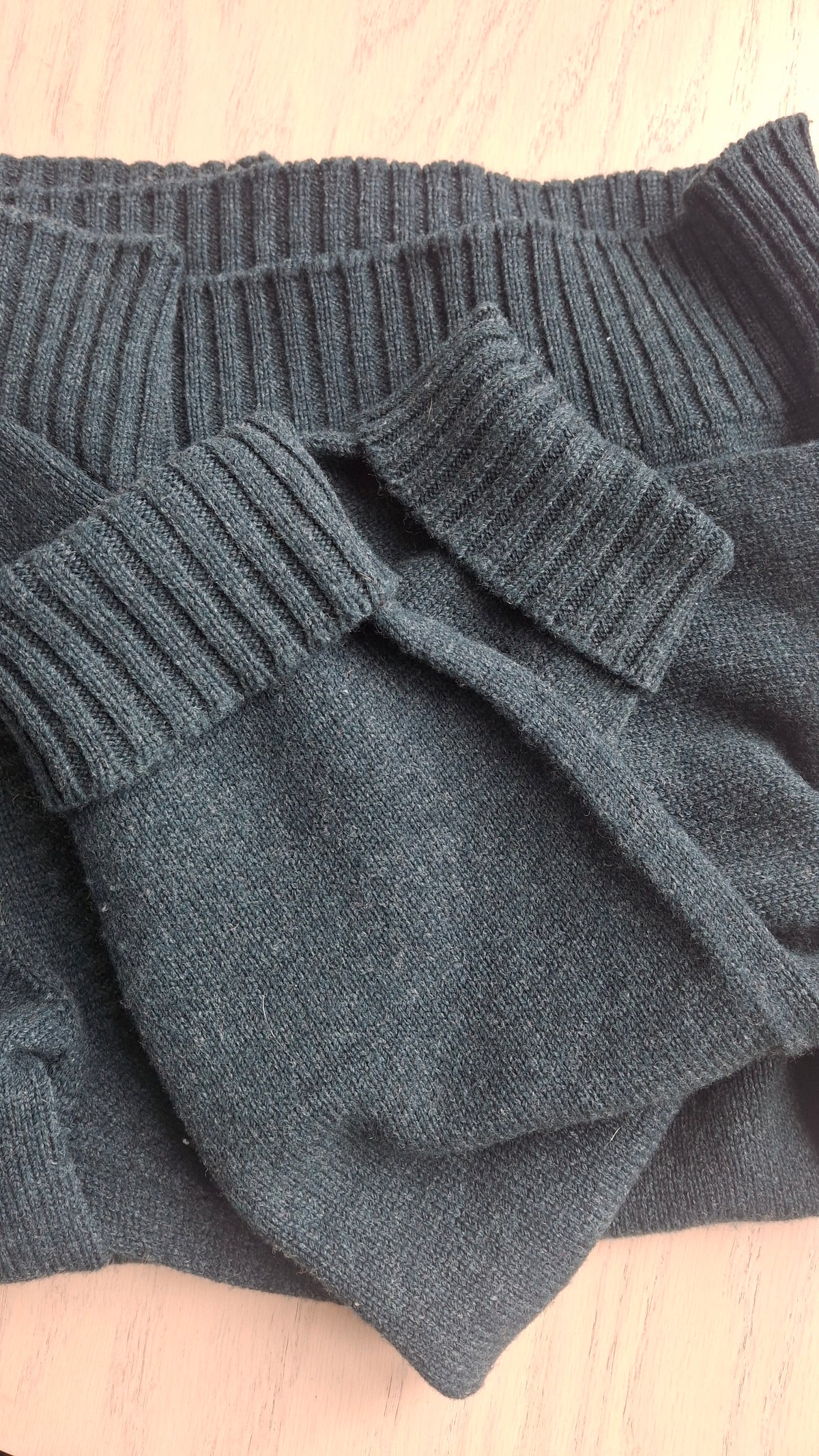 A charcoal hand-knitted jumper folded to show its ribbed cuffs